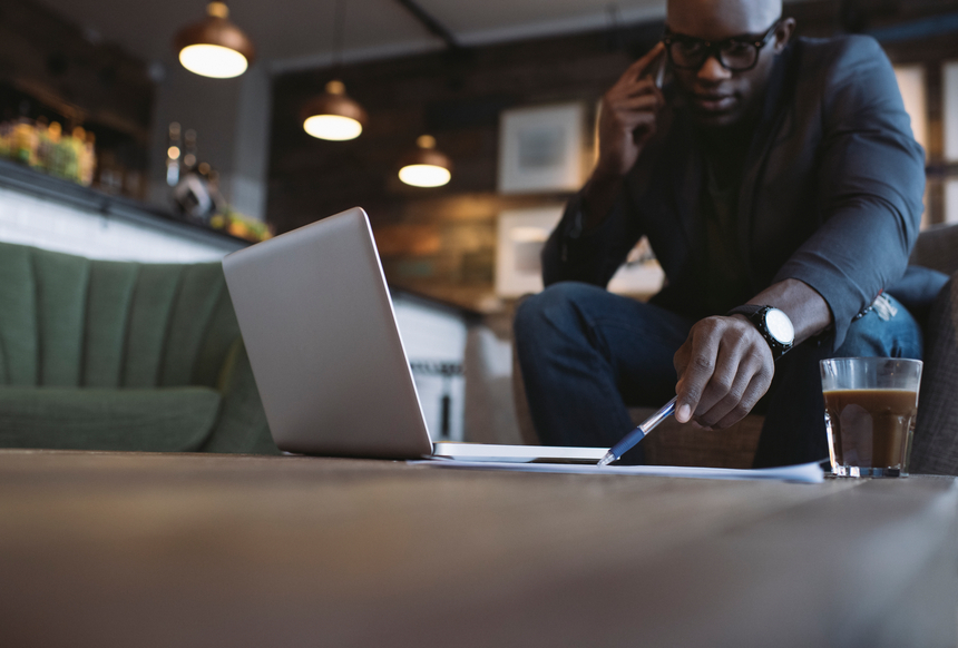 Young businessman at cafe talking on phone and pointing at a doc