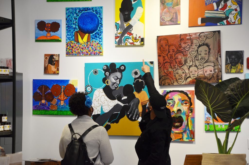 Brian Roberts, The Black Pantry, right, showing artwork to the store's first-ever customer Thursday