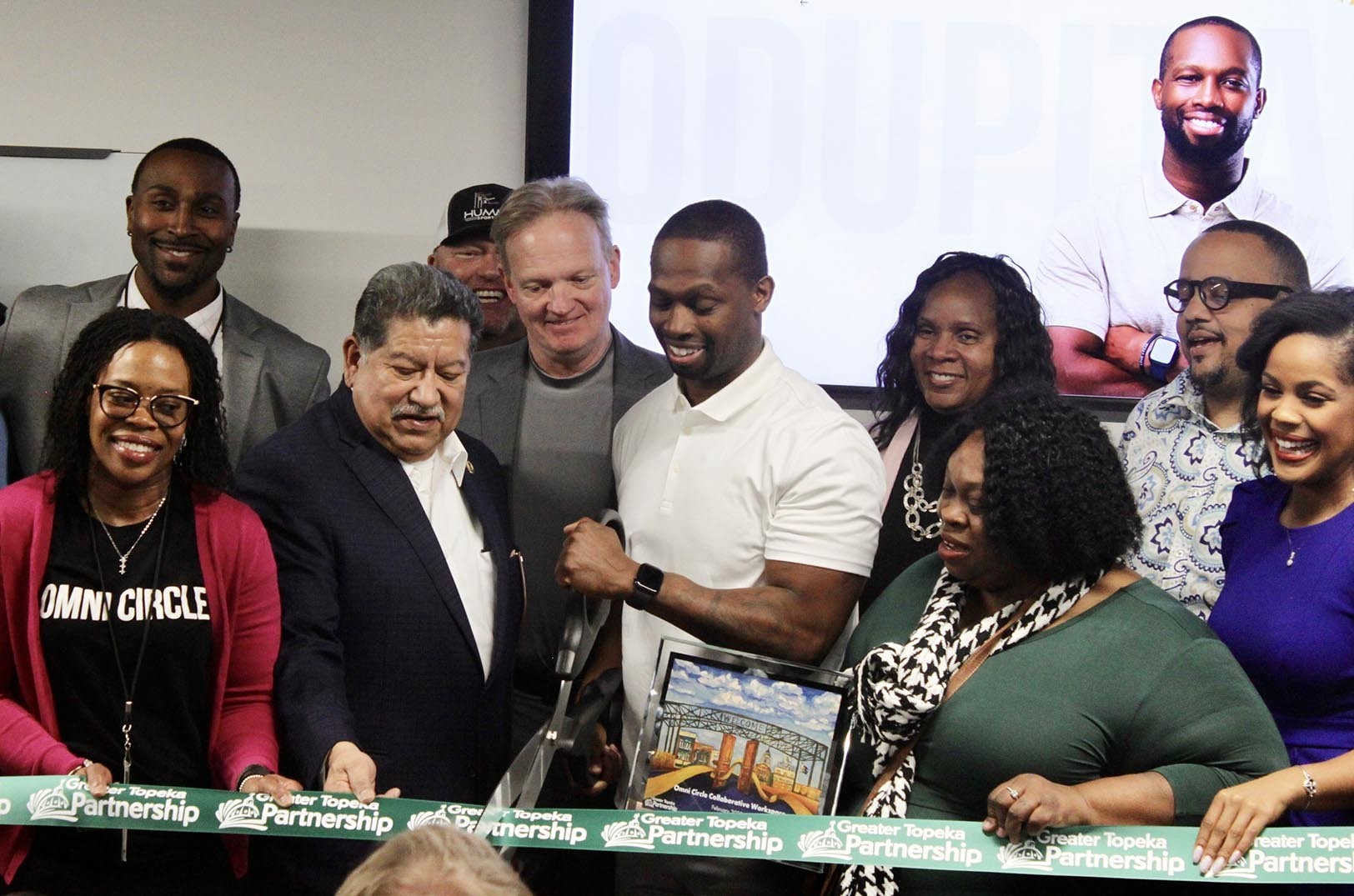 Michael Odupitan, Omni Circle Group, center, joined by Topeka Mayor Mike Padilla and other local officials, cuts the ribbon on Omni Circle Group's new space