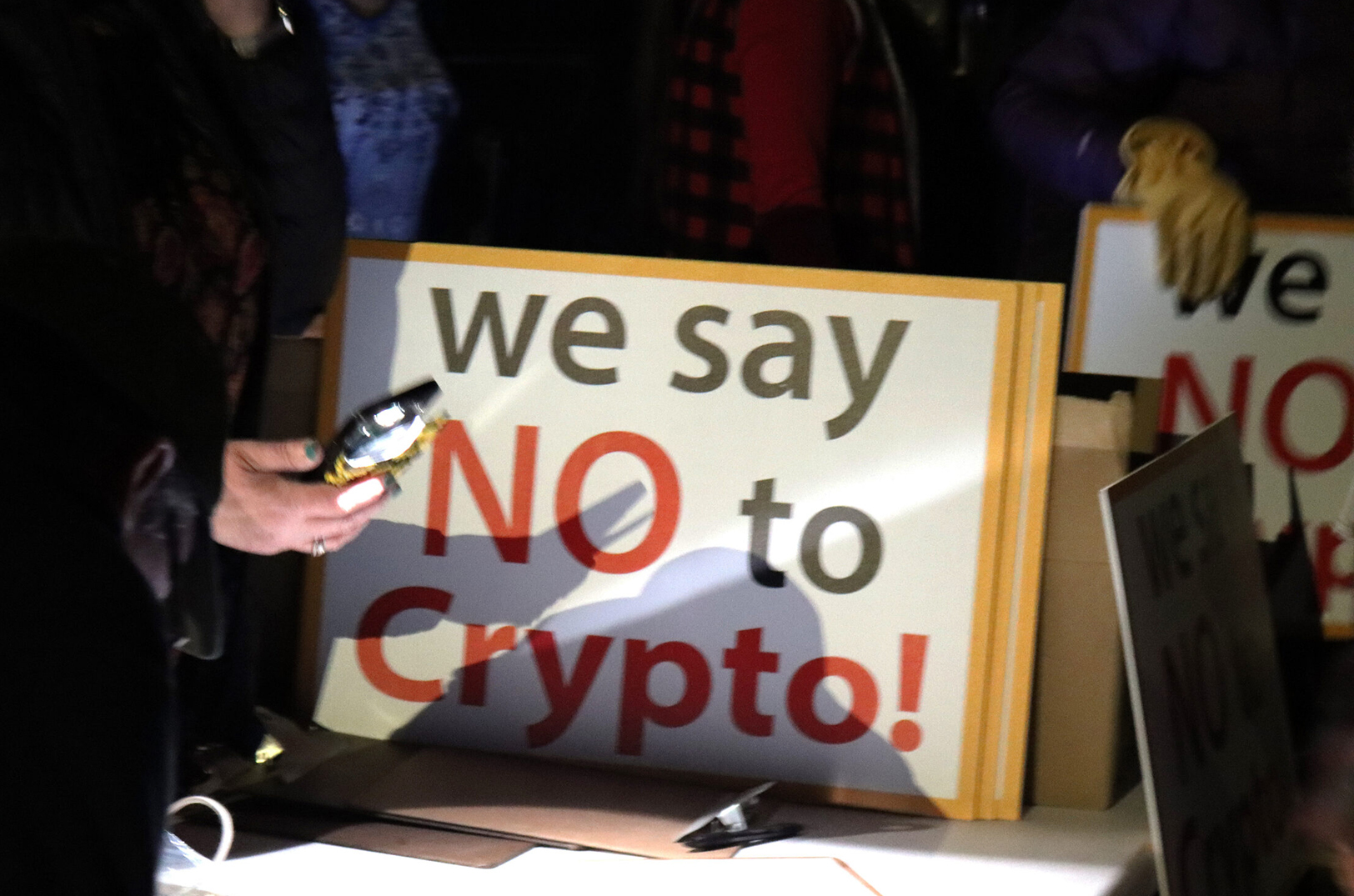 Folks sign petitions and buy "no crypto" signs before the McLouth City Council meeting last week; Photo by Cami Koons, Flatland, Kansas City PBS