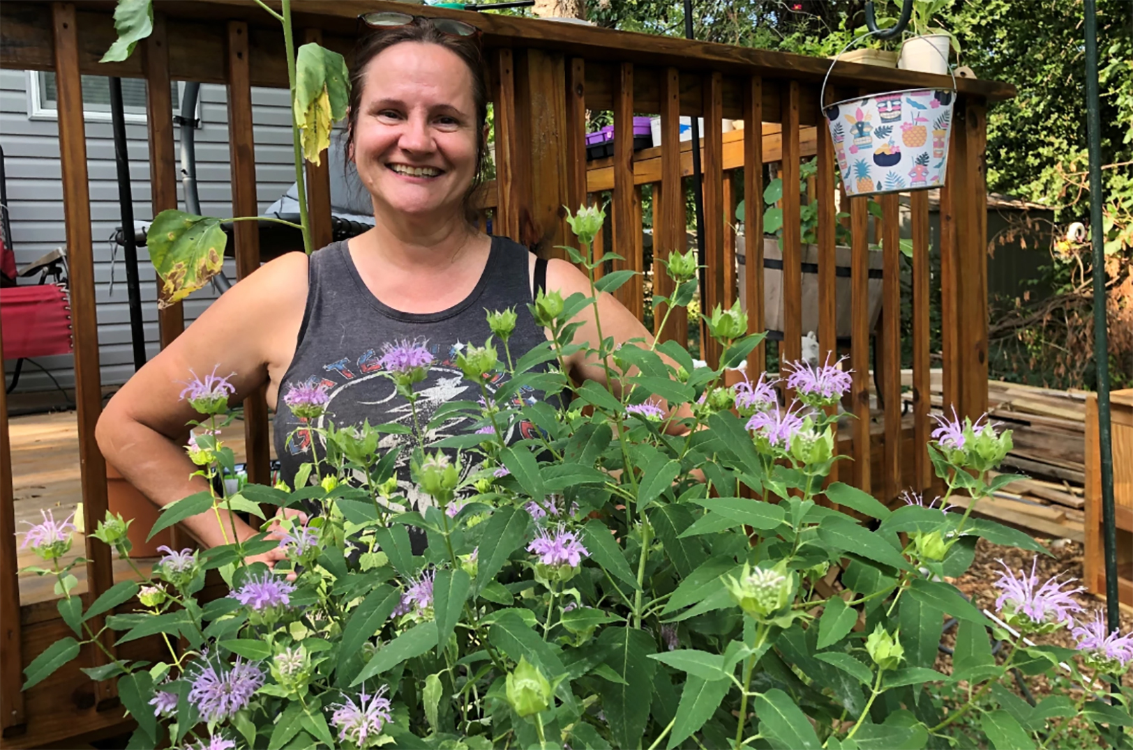 Ellen Finnerty poses with native wildflowers she planted to support pollinators. Finnerty wants to keep bees in her yard and sell the honey; photo by Celia Llopis-Jepsen, Kansas News Service