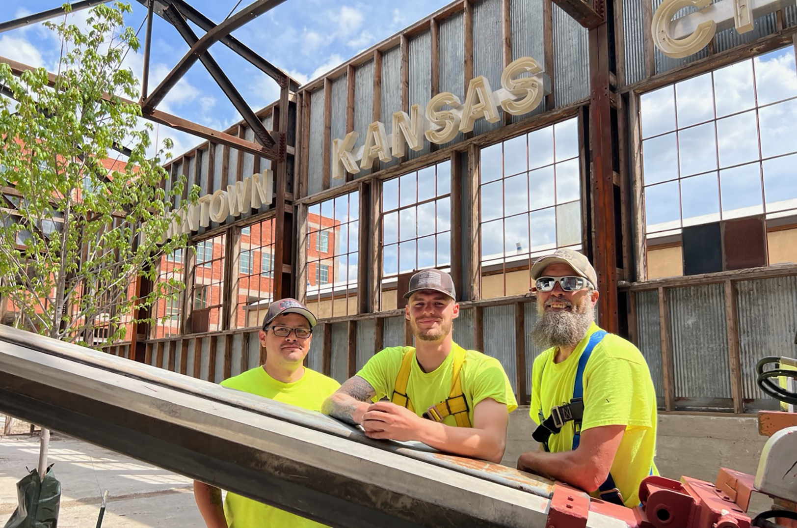 A crew from Midwest Signs poses at the future Lumi Neon Alley with a just-hung restored wordmark sign formerly from the Kansas City Downtown Airport; photo courtesy of The Lumi Neon Museum 