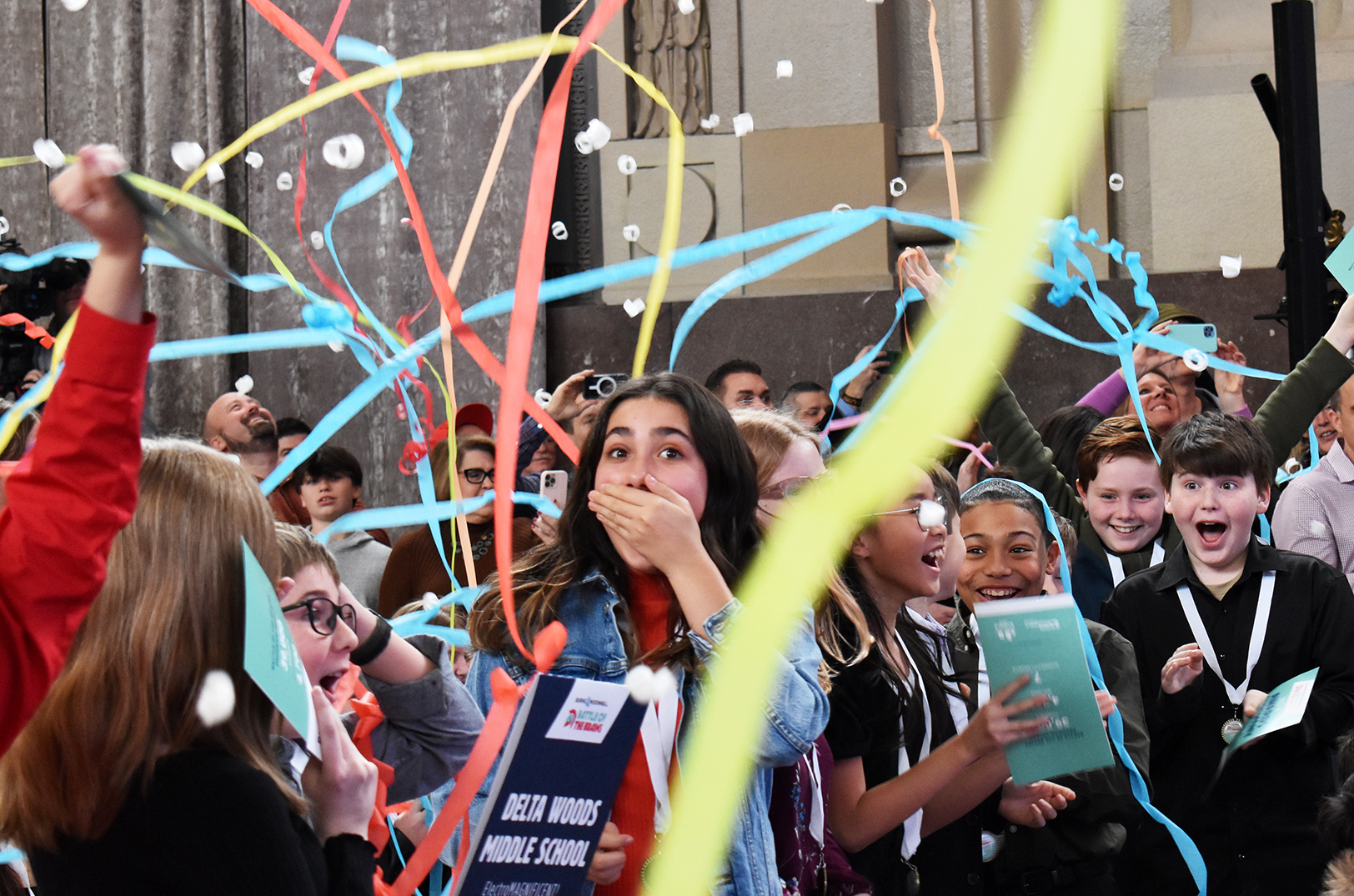 Reese Moreno, a Delta Woods Middle School student, center, reacts to her team winning Burns & McDonnell’s Battle of the Brains competition; photo by Taylor Wilmore, Startland News