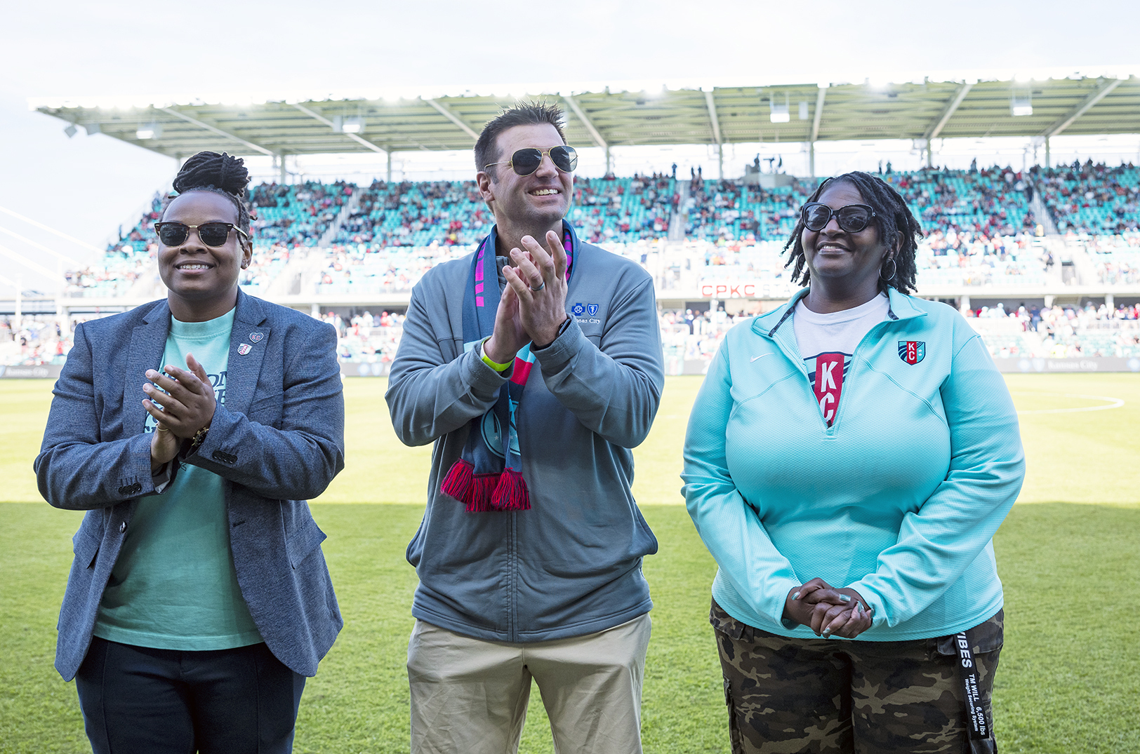 Tammy Buckner, WeCode KC, right, is honored March 30 on the field by DePrice Taylor, executive director of community relations for the KC Current; and Chad Waller, sports partnership manager for Blue KC; photo courtesy of Blue KC