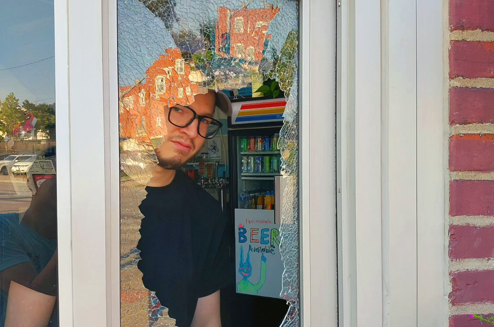 A worker at Anchor Island Coffee looks through the shattered window of the shop at 4101 Troost Ave. after an overnight break-in; photo courtesy of Anchor Island Coffee