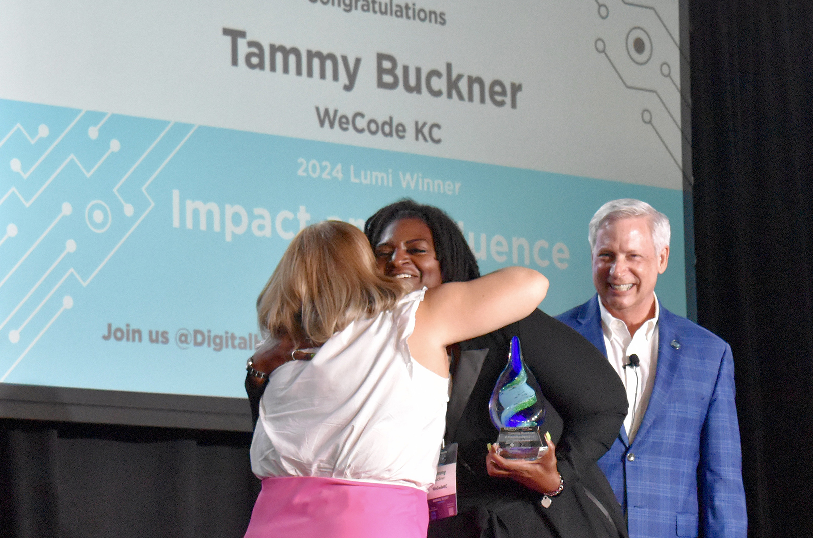 Tammy Buckner, WeCodeKC, center, accepts the Impact and Influence honor from Kara Lowe, KC Tech Council, and Dick Flanigan, Digital Health KC, during the 2024 Lumi Awards presentation; photo by Nikki Overfelt Chifalu, Startland News