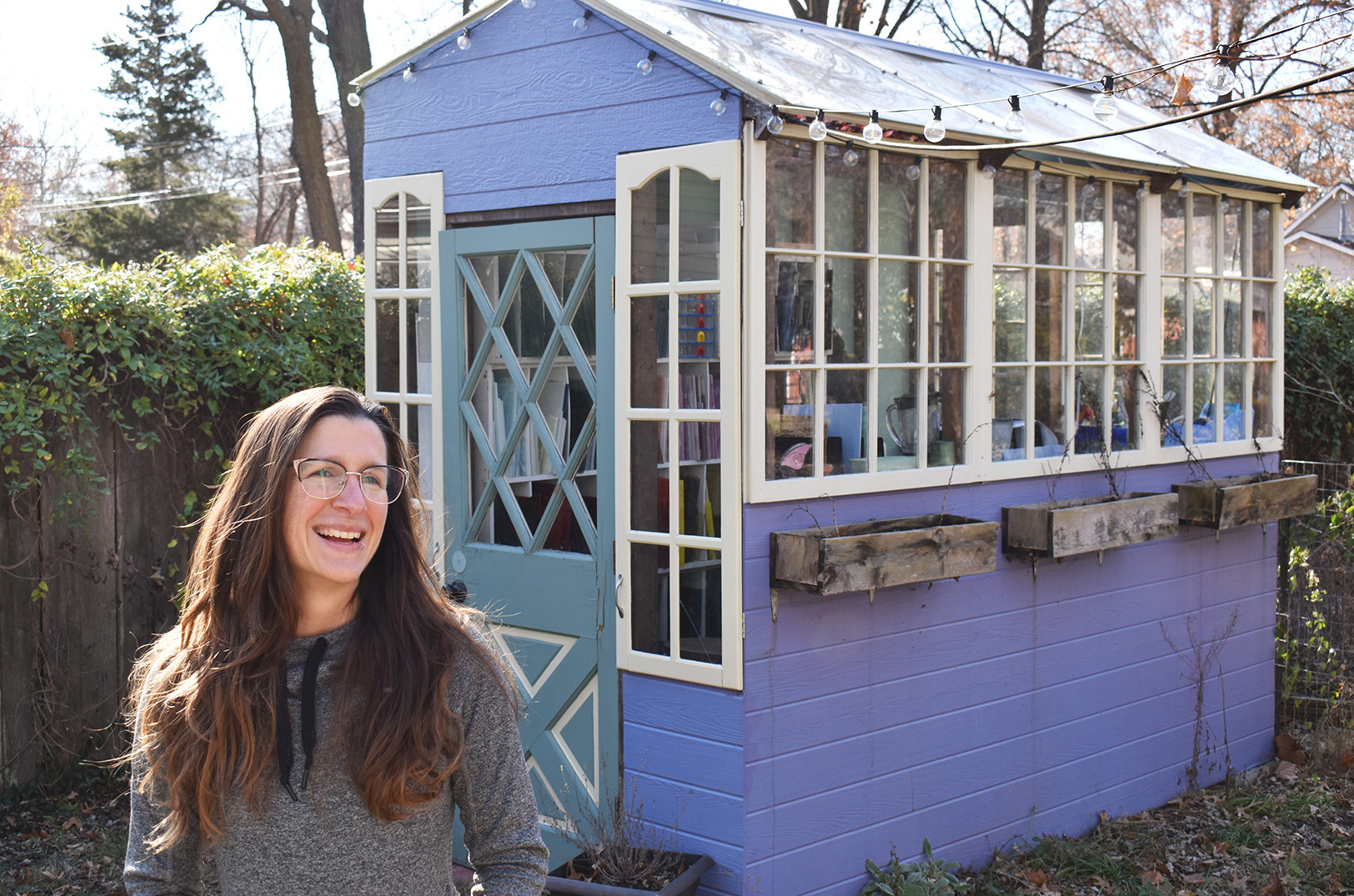 Darleen Schillaci, the stained glass artist behind  Artistained Glass, laughs outside her Lawrence workspace; photo by Tommy Felts, Startland News