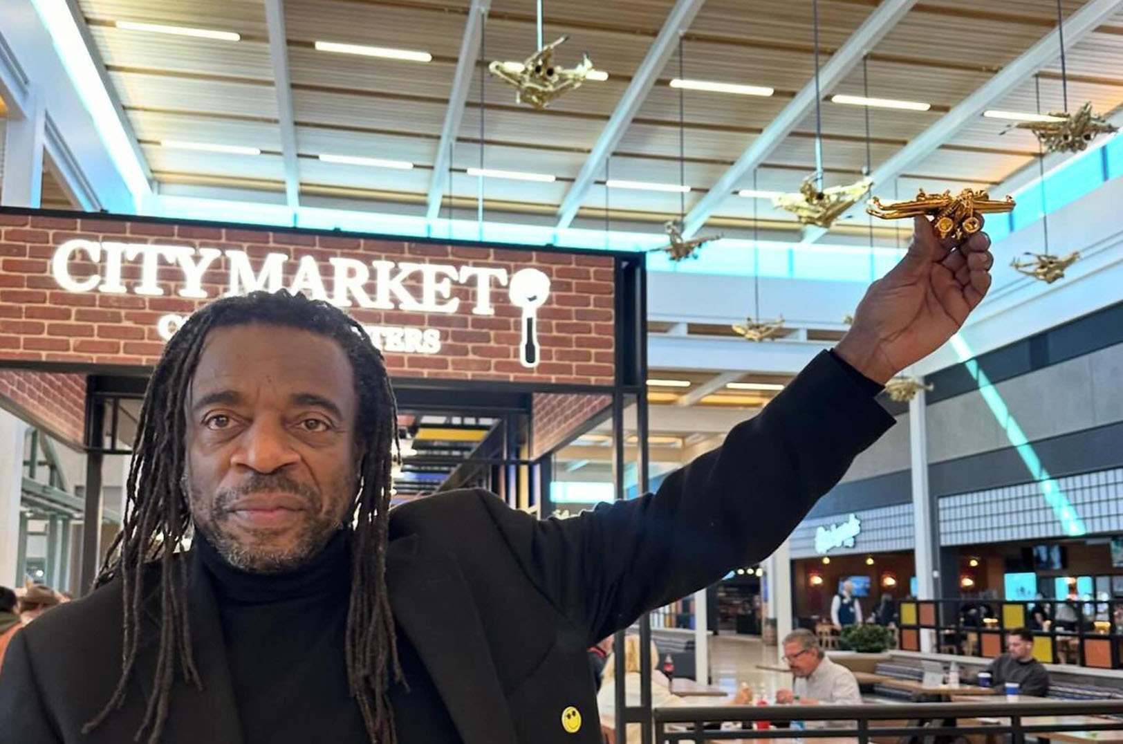 Sculptor Willie Cole holds up one of his jazz bird ornaments alongside pieces within the larger-than-life "Ornithology" installation at the Kansas City Airport's new terminal; courtesy photo