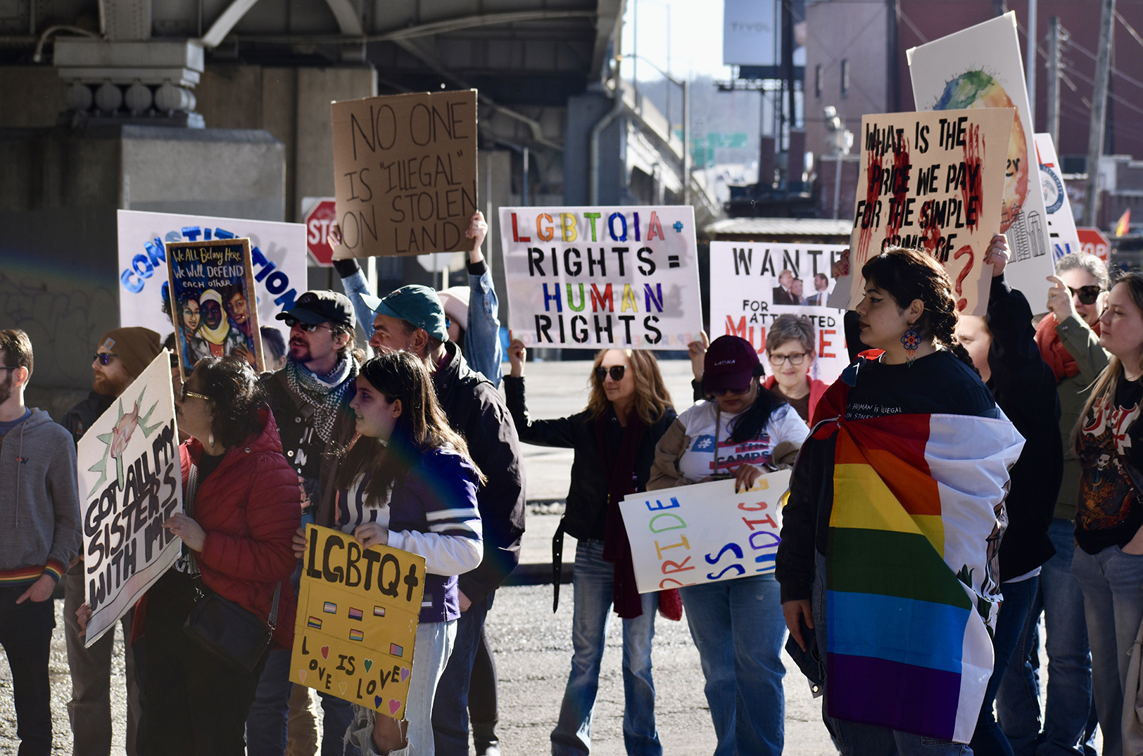 Community members gather with political signs in the Westside neighborhood under an I-35 overpass during the Unidos Rally for Immigrants and LGBTQIA+ Rights; photo by Nikki Overfelt Chifalu, Startland News