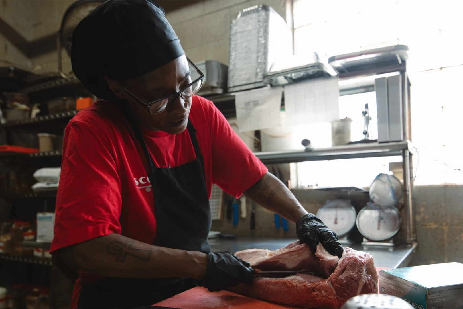Veronica Scroggins trims brisket at Scott’s Kitchen & Catering at Hangar 29 in Kansas City, North; photo by Chase Castor, Flatland