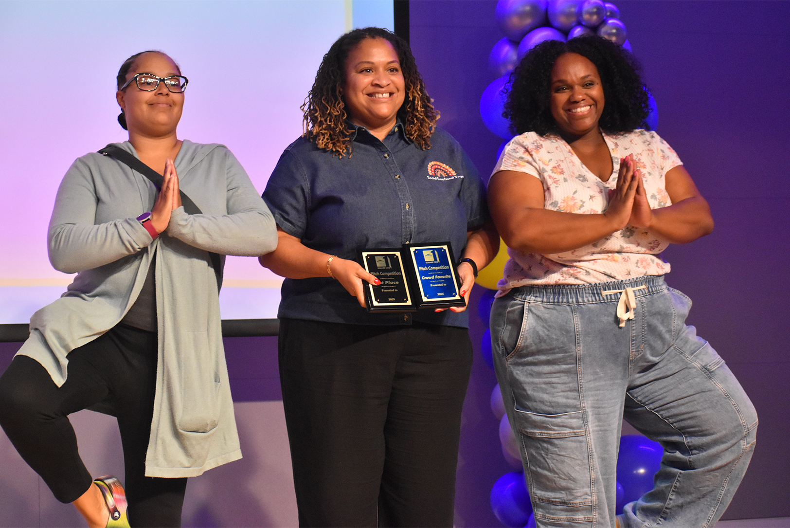 Rasheedah Villarreal, founder of Social Emotional Yoga with Mrs. V, center, accepts the first place and crowd favorite awards at the Mid-Continent Public Library’s Square One Pitch Competition; photo by Taylor Wilmore, Startland News